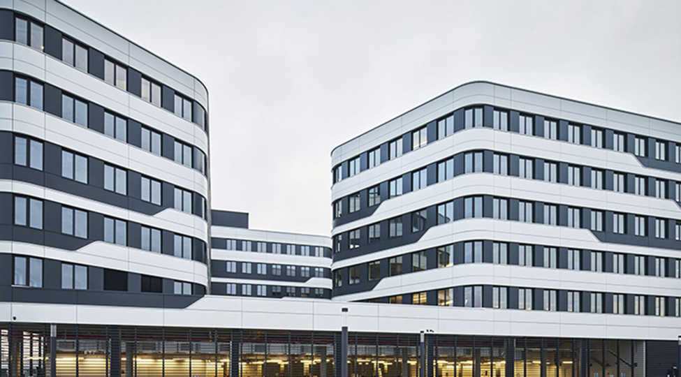 Großaufnahme des Skoda Hauptquartiers in Tchechien, stark bewölkter, grauweißer Himmel, typisches Bürogebäude in weiß mit vielen Fenstern
